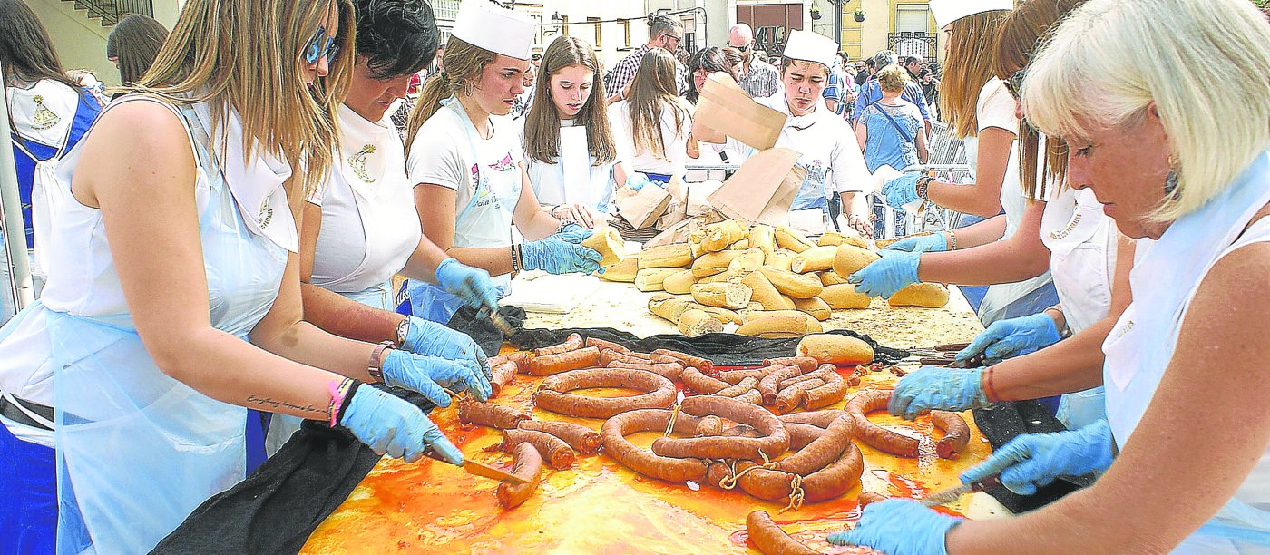 Un grupo de miembros de la Peña Los Parrales preparanlas raciones para su entrega. / JUSTO RODRÍGUEZ