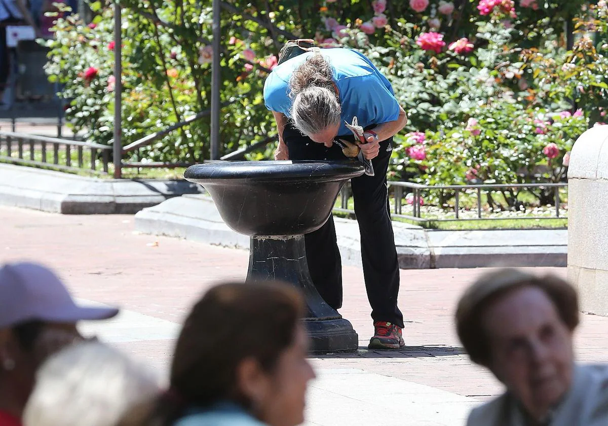 Un hombre se refresca en una fuente del Espolón.