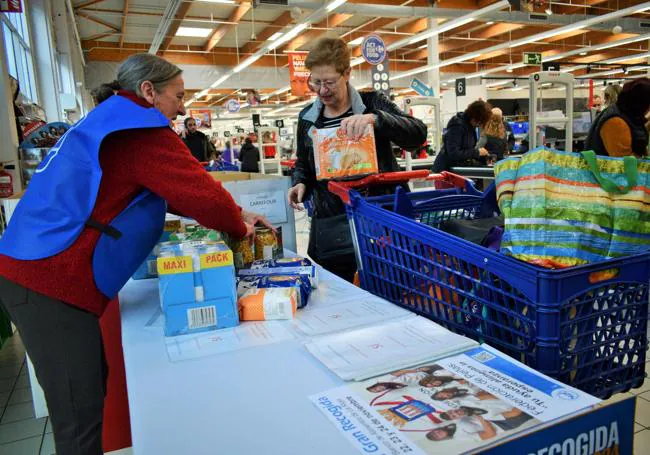 Arriba, Emma dona unos botes de garbanzos y leche, entre otras cosas, en el Carrefour del Berceo, en Logroño. Abajo, Sandra colabora con legumbres y galletas en Alcampo.